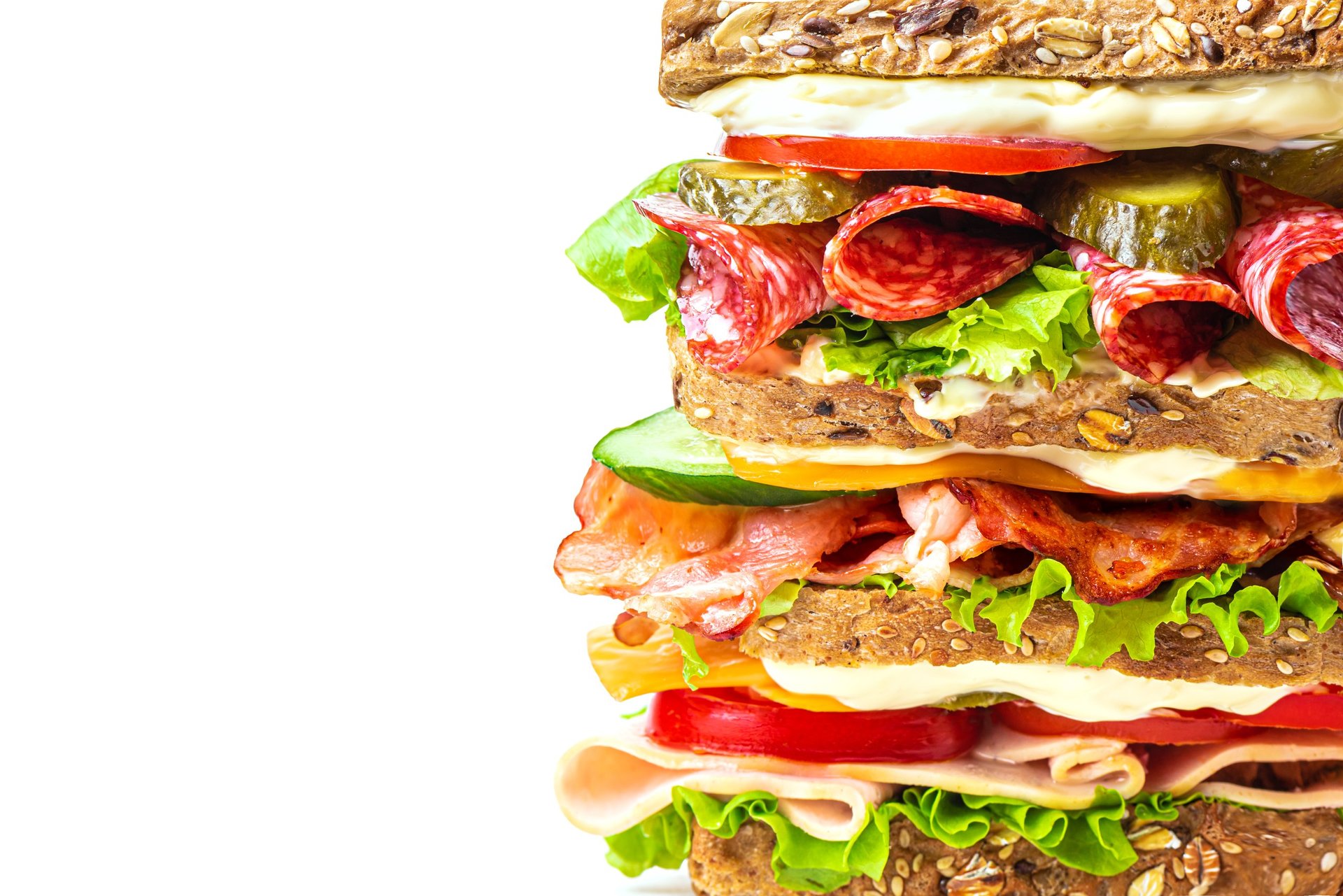 Delicious layered sandwich with ham, bacon, salami, cheese and fresh vegetables